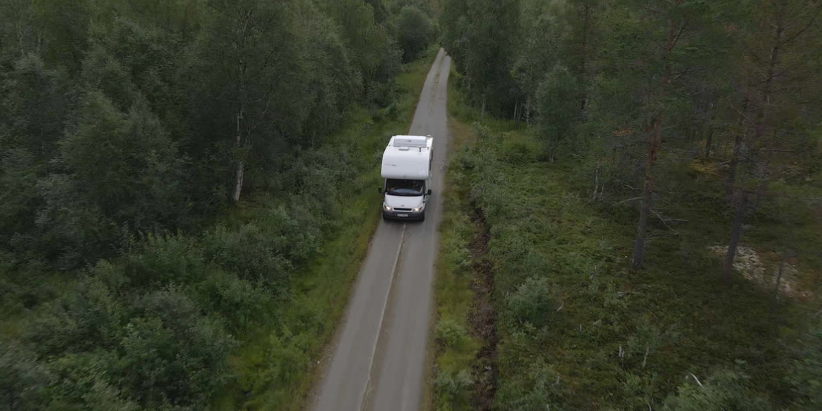 a class A rV driving down an empty wooded road that's protected with an inexpensive RV insurance policy